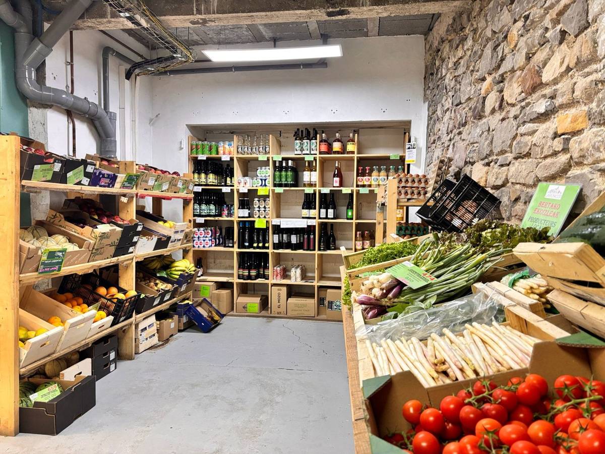L’intérieur de l’épicerie : rayons de légumes, bocaux et vins